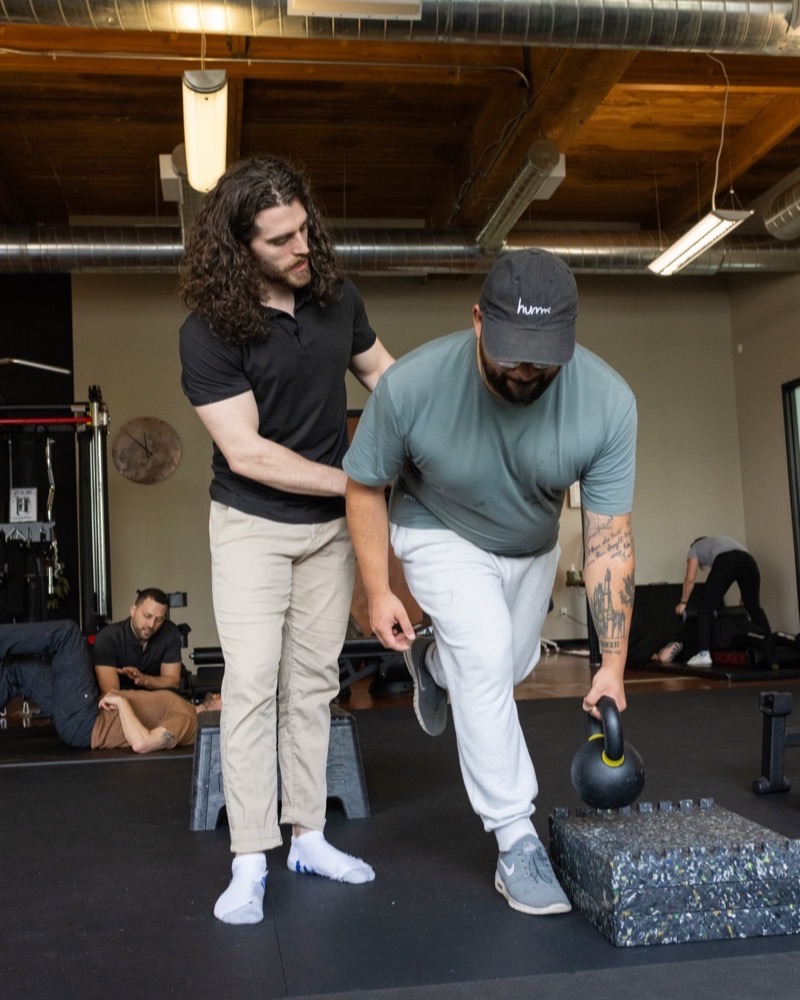 A Move Better doctor coaching a patient through a single-leg balance with a kettlebell